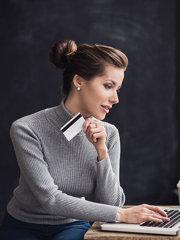 A woman holding a credit card while typing